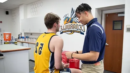 Athletic training student treating basketball player